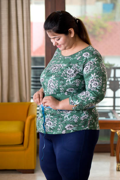 femme obèse mesurant son ventre - overweight women abdomen pot belly photos et images de collection