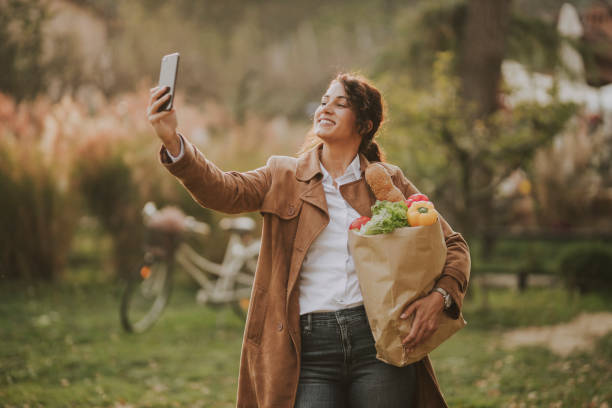 istock Woman with groceries bag taking a selfie 1187671380