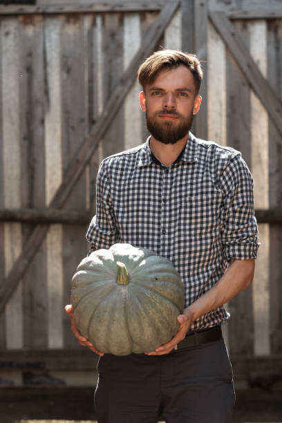 istock farmer holds a big pumpkin in his hands. 1187671451