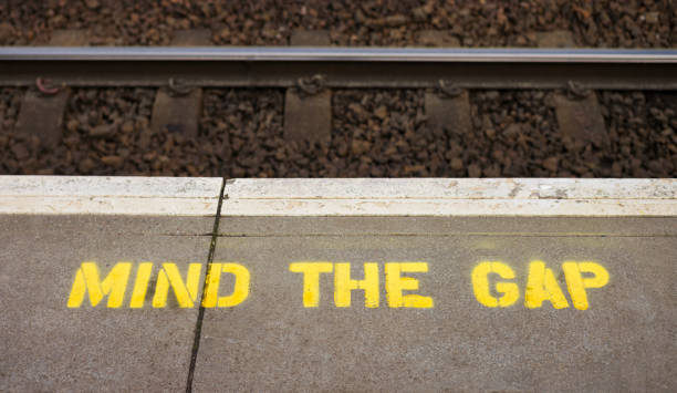 señal de advertencia mind the gap en la plataforma de la estación de tren - divergent thinking fotografías e imágenes de stock