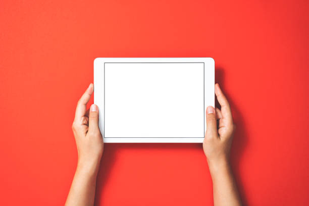 Hands holding digital tablet on red background stock photo