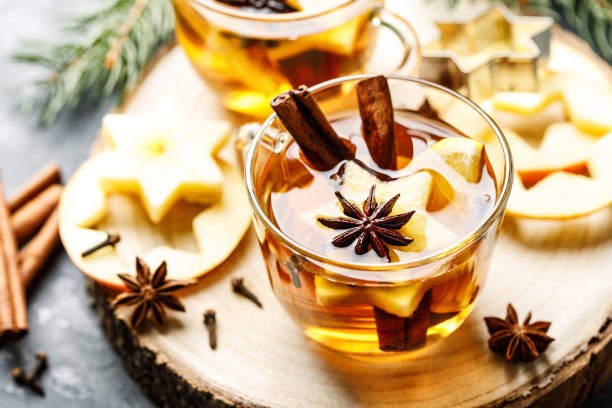 Hot drink for New Year, Christmas or autumn holidays. Mulled cider or spiced tea or mulled white wine with lemon, apples, cinnamon, anise, cloves. Hot drink for New Year, Christmas or autumn holidays. Mulled cider or spiced tea or mulled white wine with lemon, apples, cinnamon, anise, cloves. mulled wine photos stock pictures, royalty-free photos & images