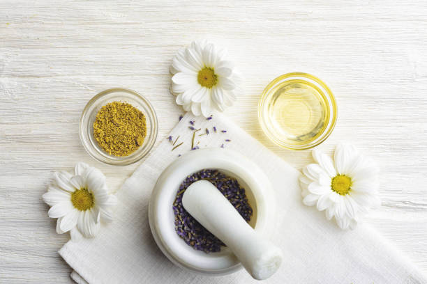 composición con flores de lavanda secas en peste de mármol blanco y mortero y aceite de manzanilla natural cosmético en frasco de vidrio sobre fondo blanco, vista superior con espacio de copia libre - mortar and pestle lavender chamomile herb fotografías e imágenes de stock