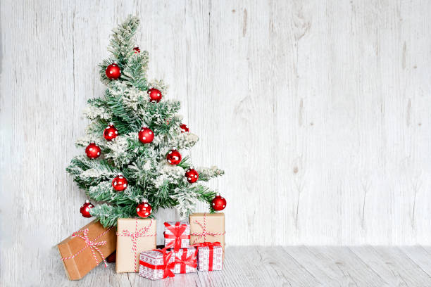 istock Selective focus Christmas tree with set of gift boxes tight with red ribbins, handmade objects on wood gray background. Christmas holiday concept. 1187674900