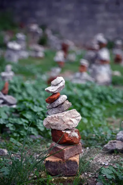 A tower of stones in the grass. Stones and bricks ordered on top of each other. Stonetower.