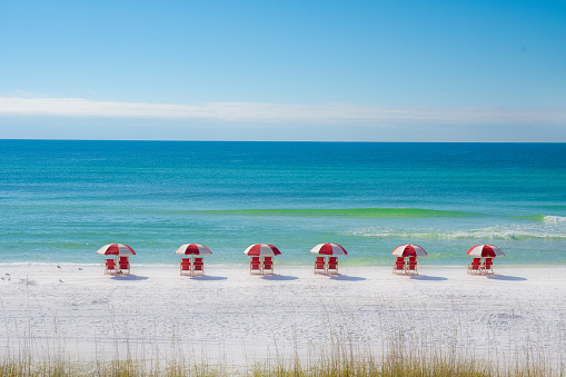 A row of chairs and umbrellas on a white sand beach.