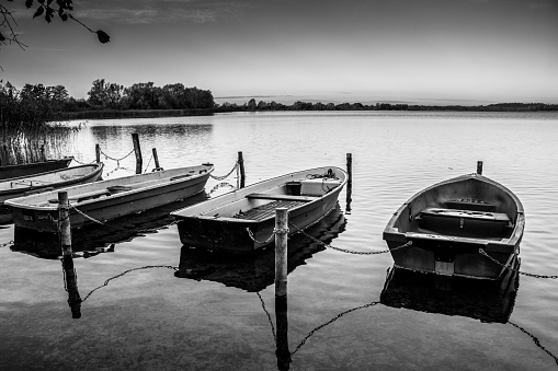 some rowboats lie at a lake in the north of Germany in the morning in autumn