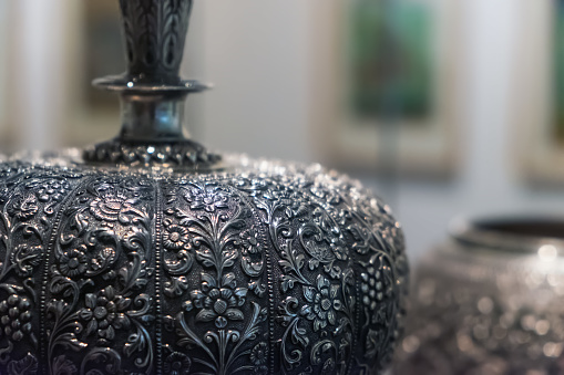 Side closeup view of a vintage jug with floral patterns. Selective focus