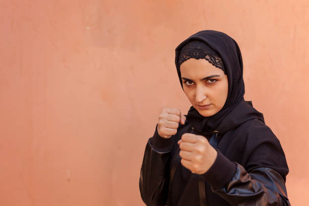 Muslim boxer woman in Islamic sportswear. Muslim fighter boxer posing doing exercises Muslim boxer woman in Islamic sportswear. Muslim fighter boxer posing doing exercises. Healthy lifestyle, sport in Islamic countries, women rights concepts boxercise stock pictures, royalty-free photos & images