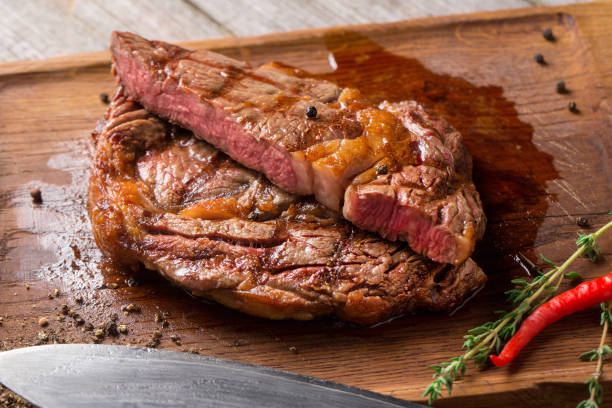 istock Cut Rib eye steak on wooden board, closeup 1187700106