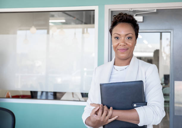 istock Beautiful businesswoman smiling in office while holding binder 1187701849