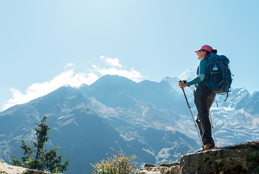 Young hiker backpacker female using trekking poles enjoying mountain view during high altitude Acclimatization walk. Everest Base Camp trekking route, Nepal. Active vacations concept image