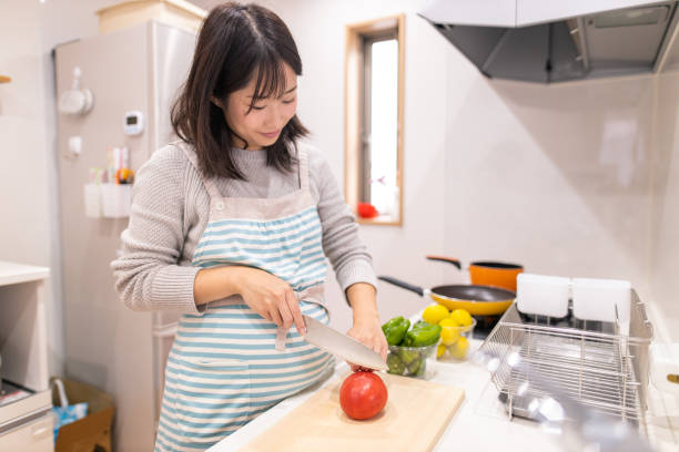 istock Pregnant woman cuttim tomato at kitchen 1187710319