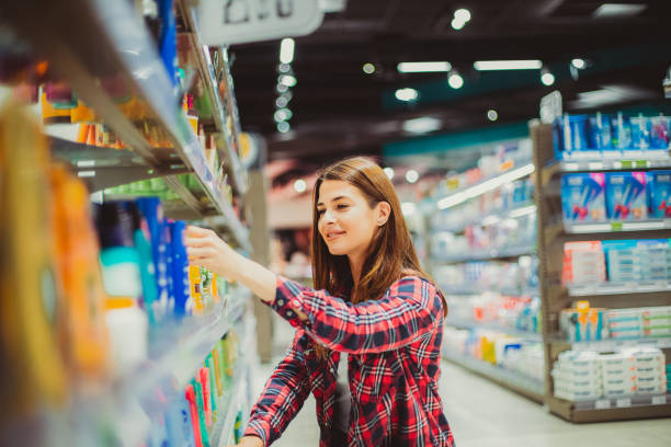 una ragazza che sceglie una lozione al supermercato - clothing uncertainty household equipment brown hair foto e immagini stock