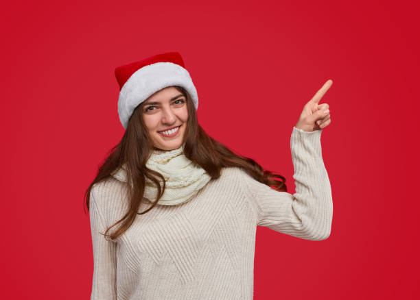 istock Smiling woman in Santa hat pointing at empty space 1187713390