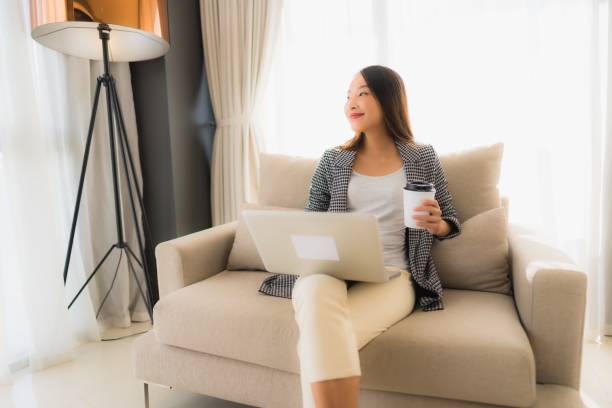istock Beautiful young asian portrait using computer and laptop with coffee cup sitting on sofa 1187733838