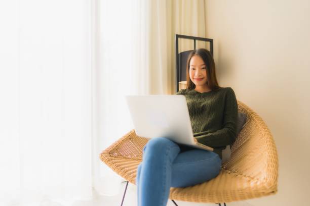 istock Portrait beautiful young asian women using computer or laptop for working and sitting on sofa chair 1187735916