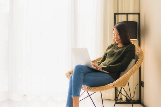 istock Portrait beautiful young asian women using computer or laptop for working and sitting on sofa chair 1187736089