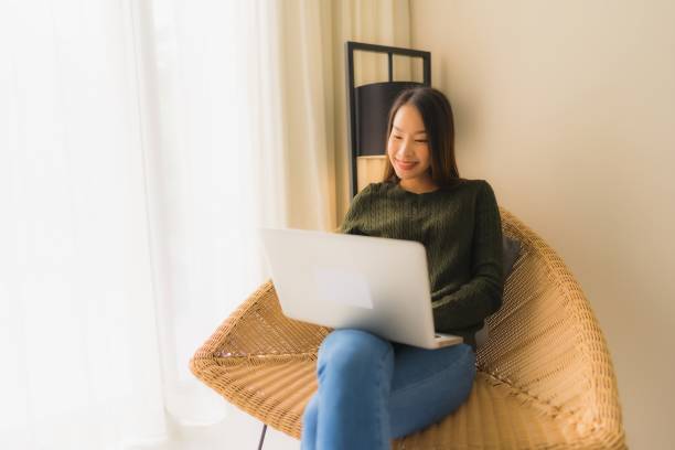 istock Portrait beautiful young asian women using computer or laptop for working and sitting on sofa chair 1187736098
