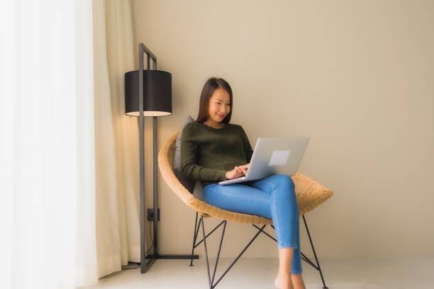 istock Portrait beautiful young asian women using computer or laptop for working and sitting on sofa chair 1187736131