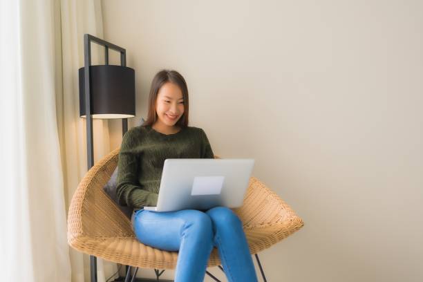 istock Portrait beautiful young asian women using computer or laptop for working and sitting on sofa chair 1187736154