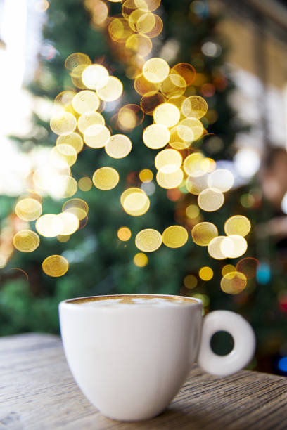 Tasty cappuccino with some blurred lights on Christmas tree. Holiday concept.