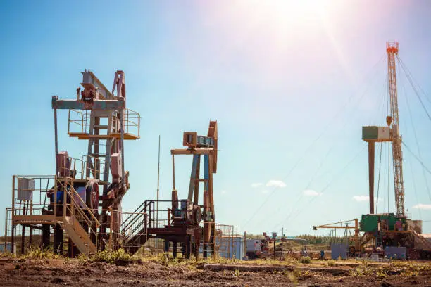 Photo of Oil pump jack rocking with pipeline in the background. Rocking machines for power generation. Extraction of oil.