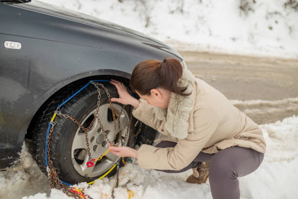 istock Beautiful woman installing snow chain on her car 1187751636