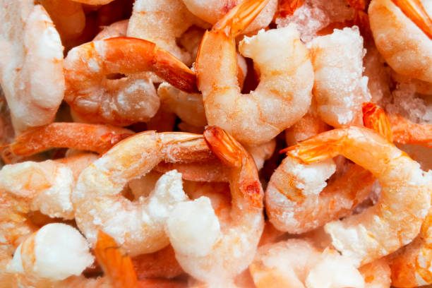Raw frozen and peeled shrimp background. Pile of frozen shrimps  .Close-up of frozen shrimps. A lot of royal shrimp macro shot stock photo