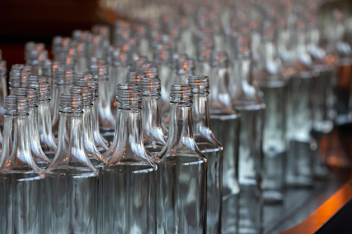 Many glass bottles on a factory conveyor.