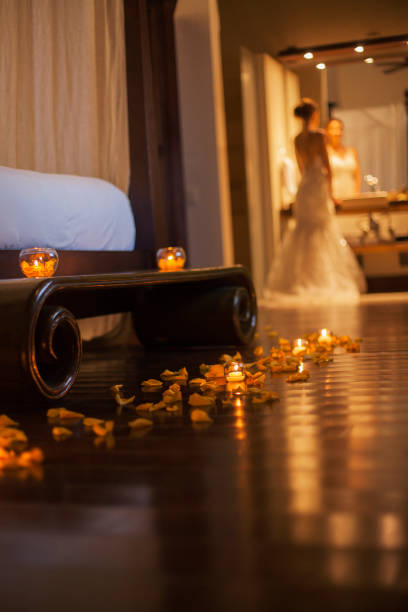 Latin woman aged 25-35 years is looking in the mirror preparing for her honeymoon is in the hotel room covered with petals