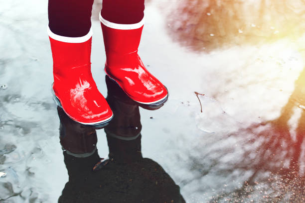 istock girl in red rubber boots standing in a puddle,close up 1187756248