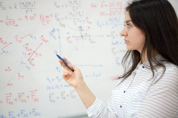 istock Female Student writing formula in front of the blackboard 1187760331