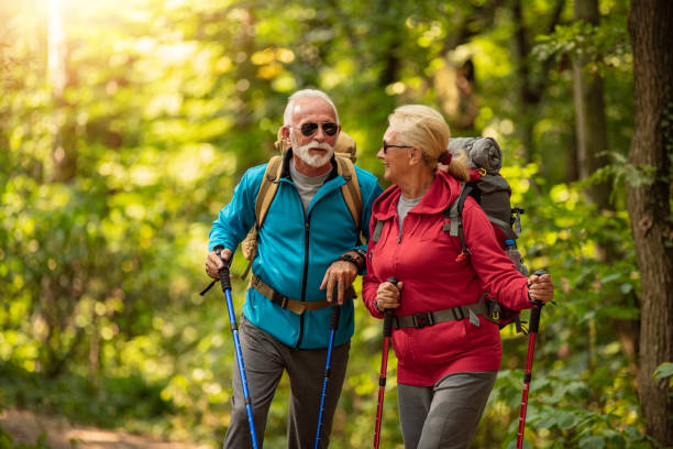 la coppia senior sta facendo escursioni nella foresta. concetto di avventura, viaggio, escursione e persone - bag senior adult outdoors friendship foto e immagini stock