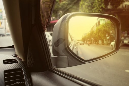Car side mirror that reflects the back image to prevent road accidents. The car's side mirror helps to make decisions for overtaking or turning, changing lane.