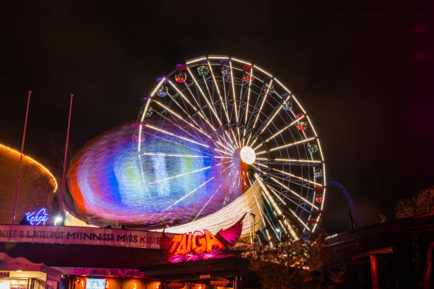 l'evento carnival of light al parco divertimenti linnanmaki. guida la ruota panoramica rinkeli e kehra in movimento, illuminazione notturna, lunga esposizione. - ferris wheel wheel blurred motion amusement park foto e immagini stock