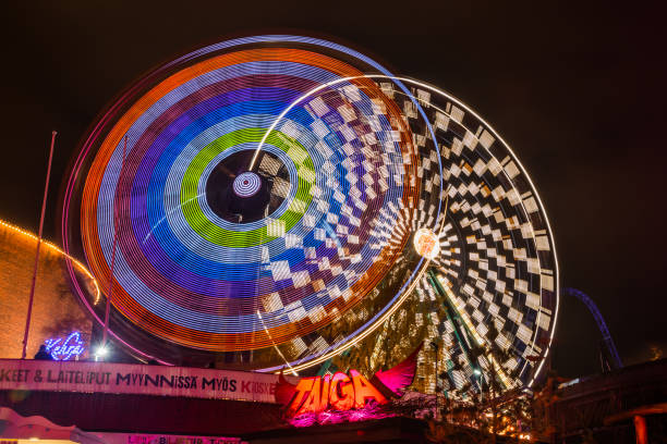 o carnaval do evento claro no parque de diversões de linnanmaki. passeio ferris wheel rinkeli e kehra em movimento, iluminação noturna, longa exposição. - ferris wheel wheel blurred motion amusement park - fotografias e filmes do acervo