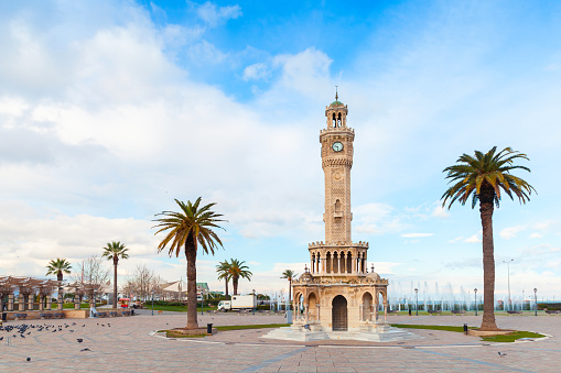 Konak Square view with palm trees and old clock tower, it was built in 1901 and accepted as the official symbol of Izmir City, Turkey