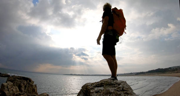 istock Mountaineer ascends to rock summit at sunrise 1187772684
