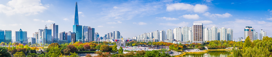Panoramic view across Olympic Park to the high-rise cityscape and iconic spire of Lotte World Tower in central Seoul, South Korea.