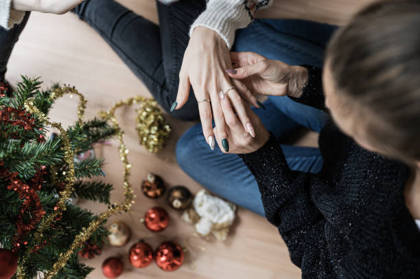 Lesbian couple getting engaged next to a Christmas tree stock photo