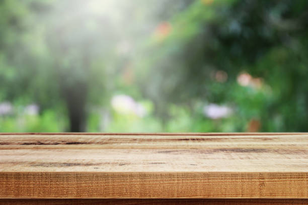 istock Blurred abstract green garden bokeh and wooden table background. 1187778917