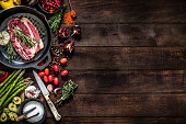 Roasting a beef steak and vegetables on an iron grill with copy space on the table