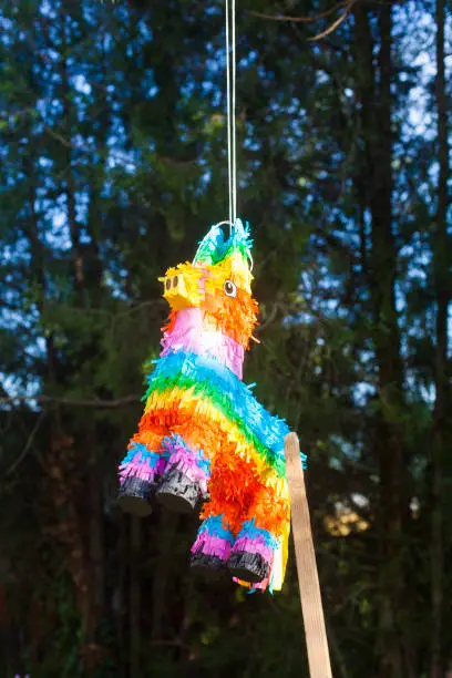 A colorful pinata in the shape of a goat hanging from the tree
