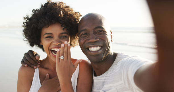 Look who's engaged! Cropped portrait of an affectionate young couple taking selfies on the beach after their engagement ring jewelry photos stock pictures, royalty-free photos & images