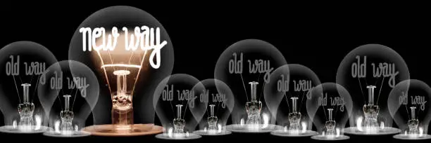 Large group of shining and dimmed light bulbs with fibers in a shape of New and Old Way words isolated on black background; concept of Innovation, Development and Success