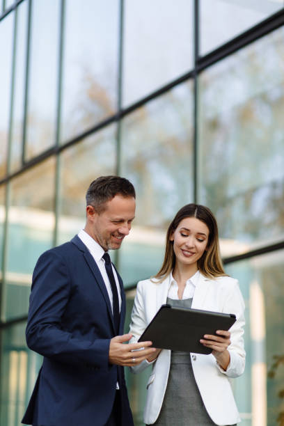istock Two business people discussing work on tablet computer outdoors 1187794819