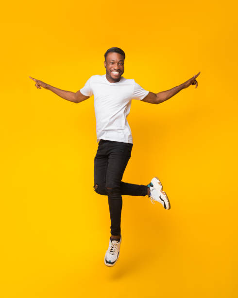 istock Cheerful Black Guy Jumping Having Fun Over Yellow Background 1187795983