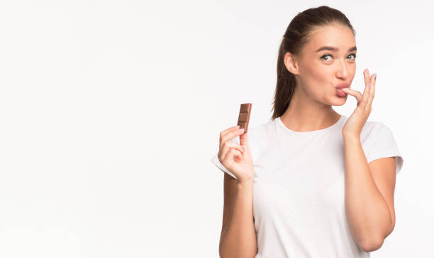 Girl Eating Chocolate And Licking Finger Standing On White Background Millennial Girl Eating Chocolate And Licking Finger Standing On White Studio Background. Copy Space chocolate fingers stock pictures, royalty-free photos & images