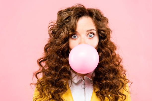 attractive surprised curly girl with bubble chewing gum, isolated on pink attractive surprised curly girl with bubble chewing gum, isolated on pink bubble gum photos stock pictures, royalty-free photos & images